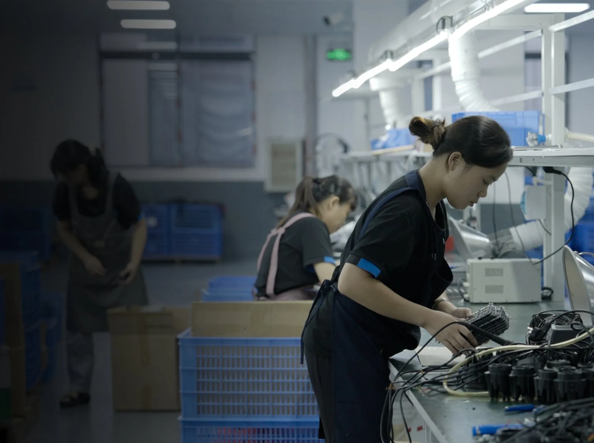 DXZ operators assembling and checking automotive LED lighting units on the production line during in-house quality control.